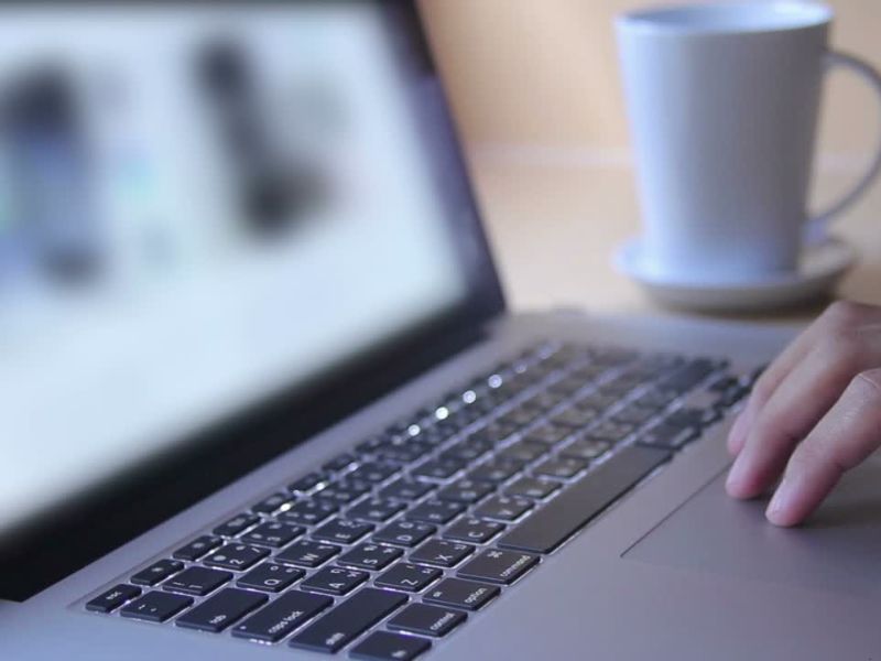 Devojka koristi laptop, pored nje bela šolja