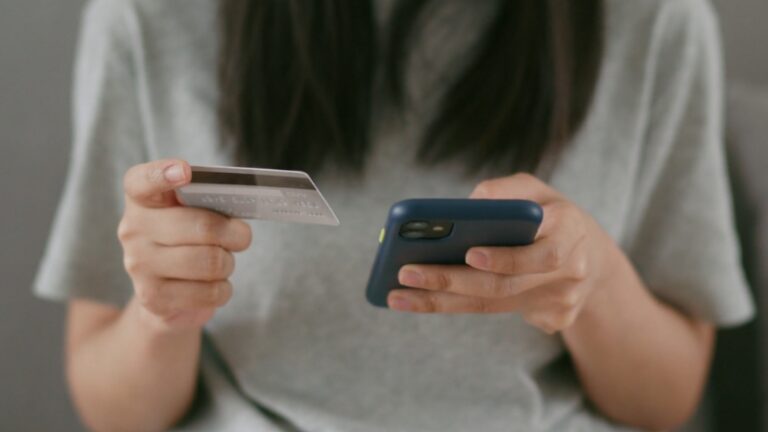 Žena drži telefon i karticu, dok kupuje dušek online